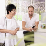 Eine Kundin steht neben einem Berater im Kundencenter